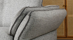 Close-up van de armleuning van de Hoekbank Charm, uitgevoerd in lichtgrijze stoffering met subtiele naden voor een luxe afwerking. Het detail toont de comfortabele en stijlvolle constructie van de bank, ideaal voor een modern interieur.