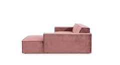 Zijaanzicht van de Hoekbank Sense met chaise longue rechts, in een warme roze bekleding. De bank heeft een strak, minimalistisch ontwerp met brede armleuningen, wat zorgt voor een moderne en comfortabele uitstraling in eigentijdse woonruimtes.