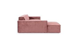 Zijaanzicht van de Hoekbank Sense met chaise longue links, uitgevoerd in een warme roze stof. De strakke vormgeving met rechte lijnen en brede armleuningen geeft de bank een moderne en minimalistische uitstraling, perfect voor eigentijdse interieurs.