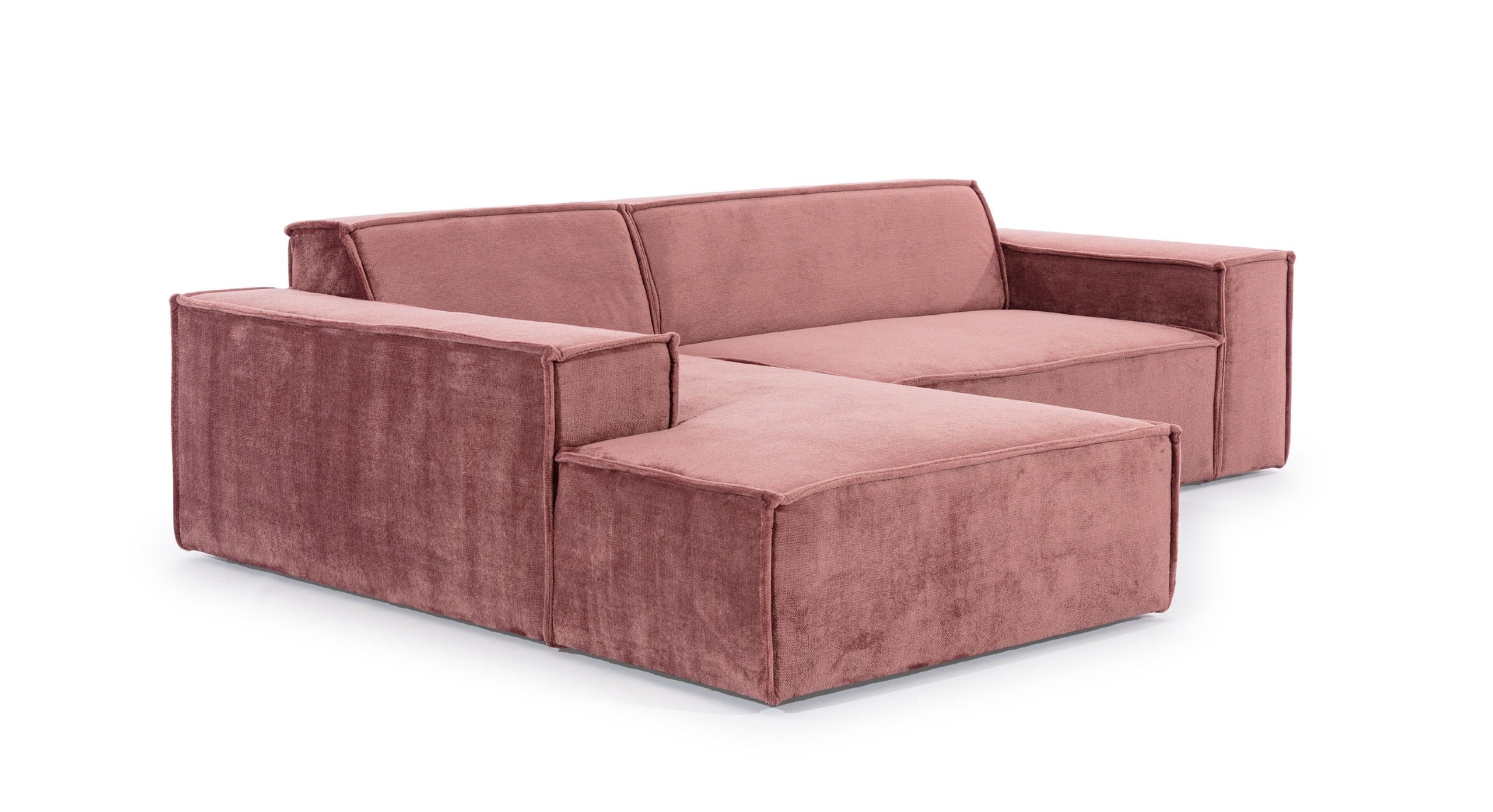 Schuin aanzicht van de Hoekbank Sense met chaise longue links, in een warme roze bekleding. De bank heeft een strak, minimalistisch ontwerp met brede armleuningen en rechte lijnen, wat een moderne en uitnodigende uitstraling geeft, ideaal voor eigentijdse interieurs.