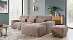 Hoekbank Fun met chaise longue rechts, afgebeeld in een moderne woonkamer met natuurlijke lichtinval. De beige bank met geribbeld stofpatroon wordt gecombineerd met een bijpassende poef en houten elementen, wat een warme en stijlvolle uitstraling aan de ruimte geeft.