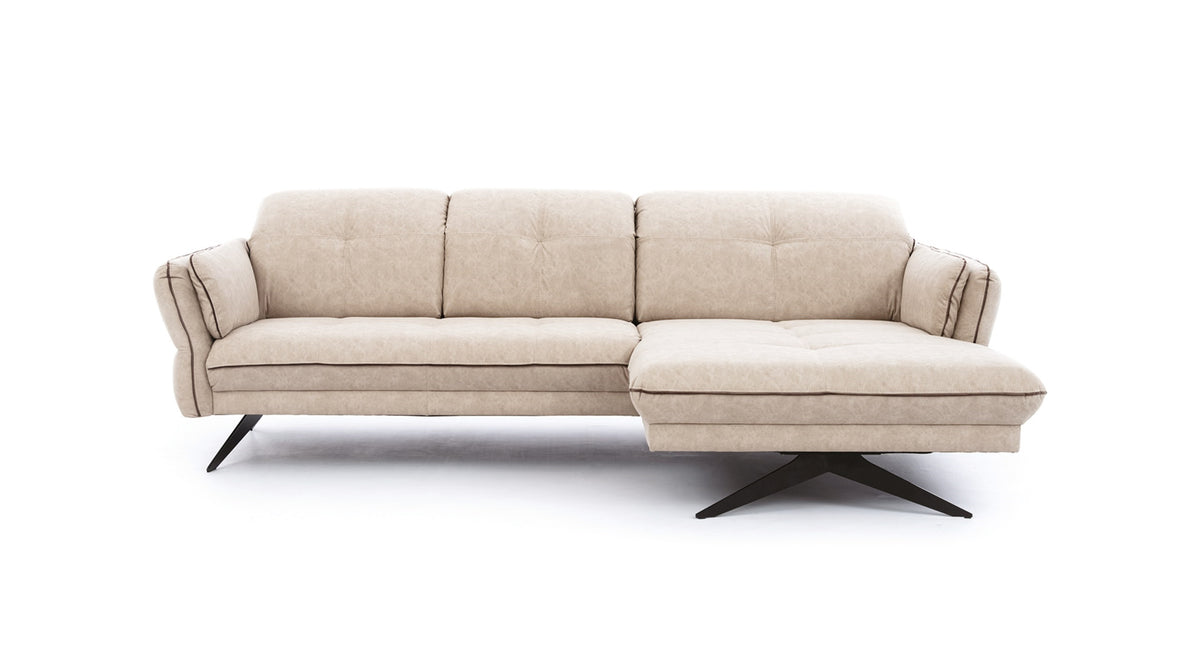 Beige hoekbank Charm met een chaise longue aan de rechterkant. De bank heeft een slanke, moderne uitstraling met zwart metalen poten en siernaden die de kussens accentueren.