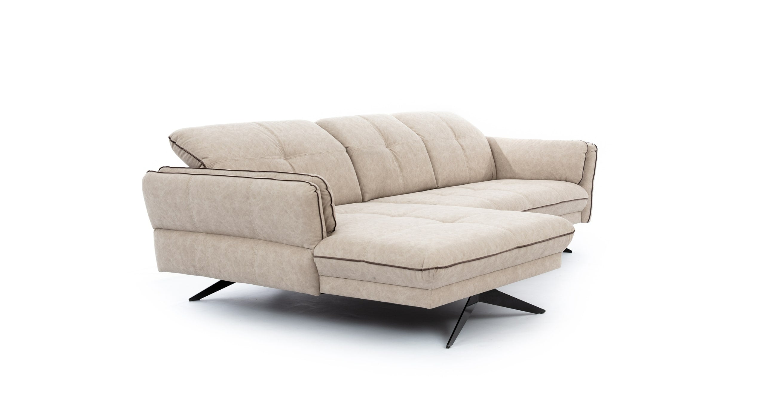 Hoekbank Charm met chaise longue links in beige stof, weergegeven in een schuine hoek om het stijlvolle design met zachte, gewatteerde zitting en rugleuning te tonen. De bank staat op zwarte, kruisvormige metalen poten, wat een modern contrast biedt met de lichte bekleding en een eigentijdse uitstraling geeft.