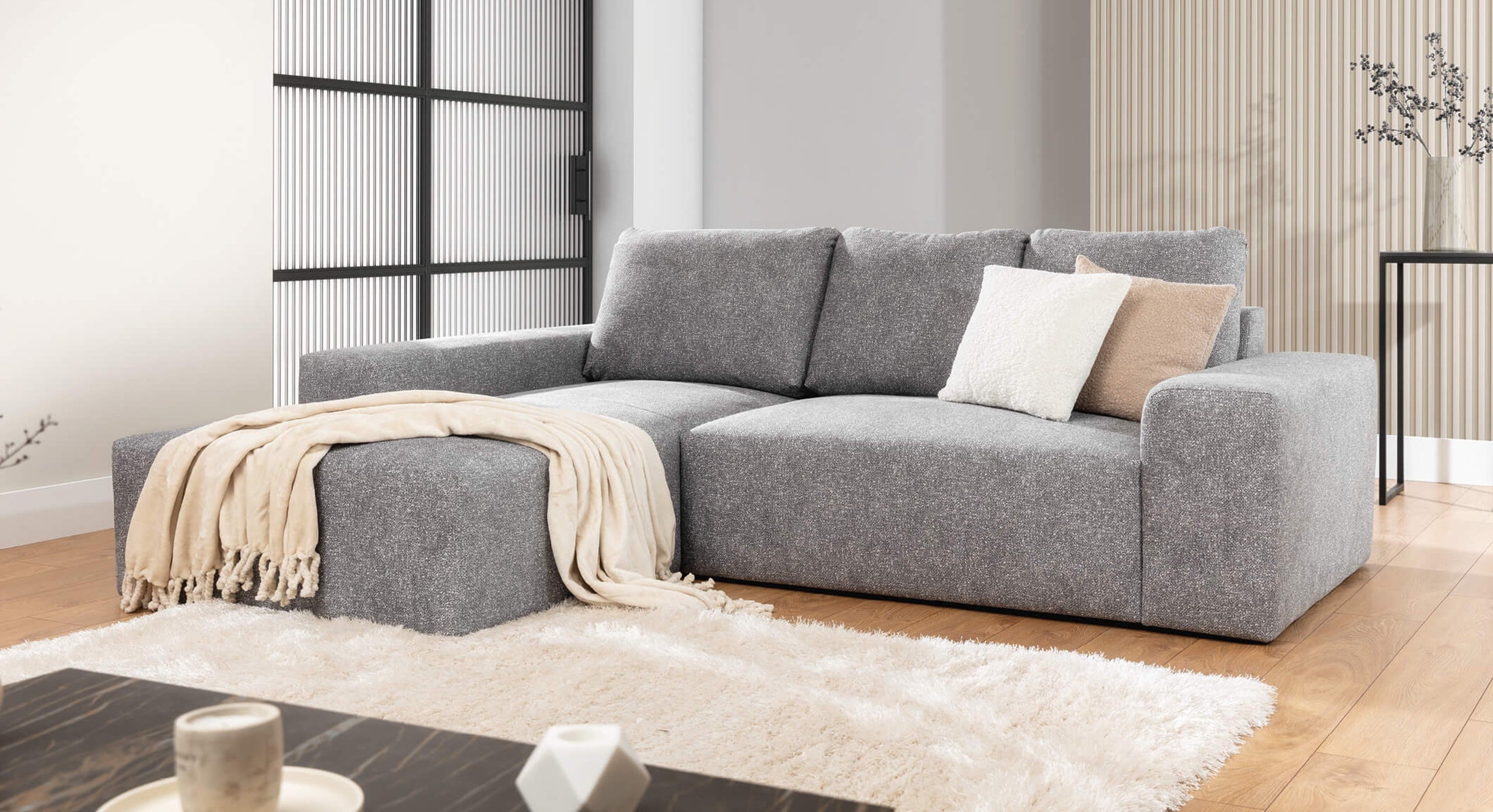 De Hoekbank Cosy Met Chaise Longue Links in een moderne woonkamer, gedecoreerd met lichte kussens en een beige plaid, geplaatst op een zacht vloerkleed voor een warme en uitnodigende sfeer.