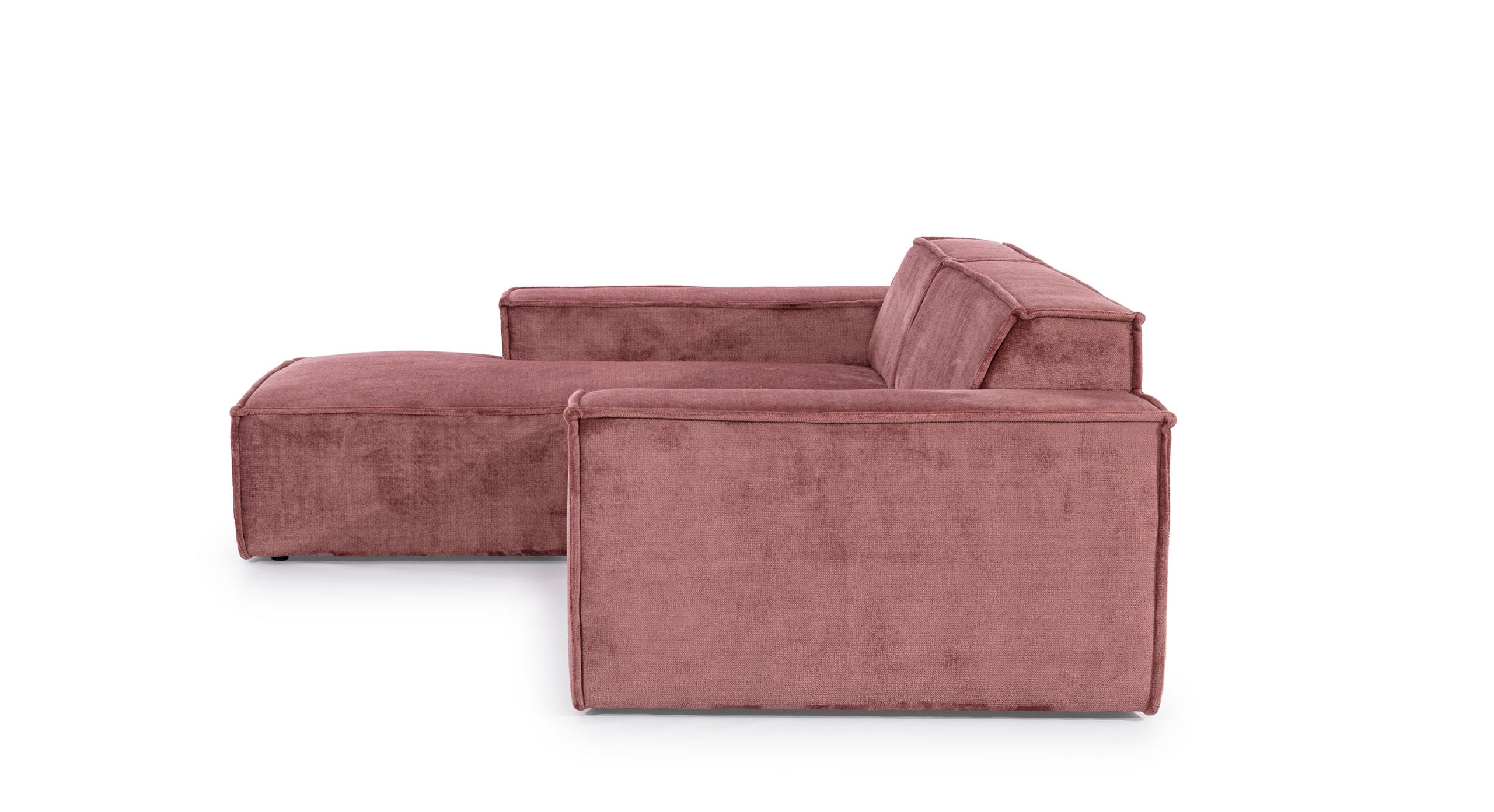 Zijaanzicht van de Hoekbank Sense met chaise longue links, uitgevoerd in een warme roze stof. De strakke lijnen en brede armleuningen benadrukken het minimalistische en moderne ontwerp, geschikt voor eigentijdse woonruimtes.