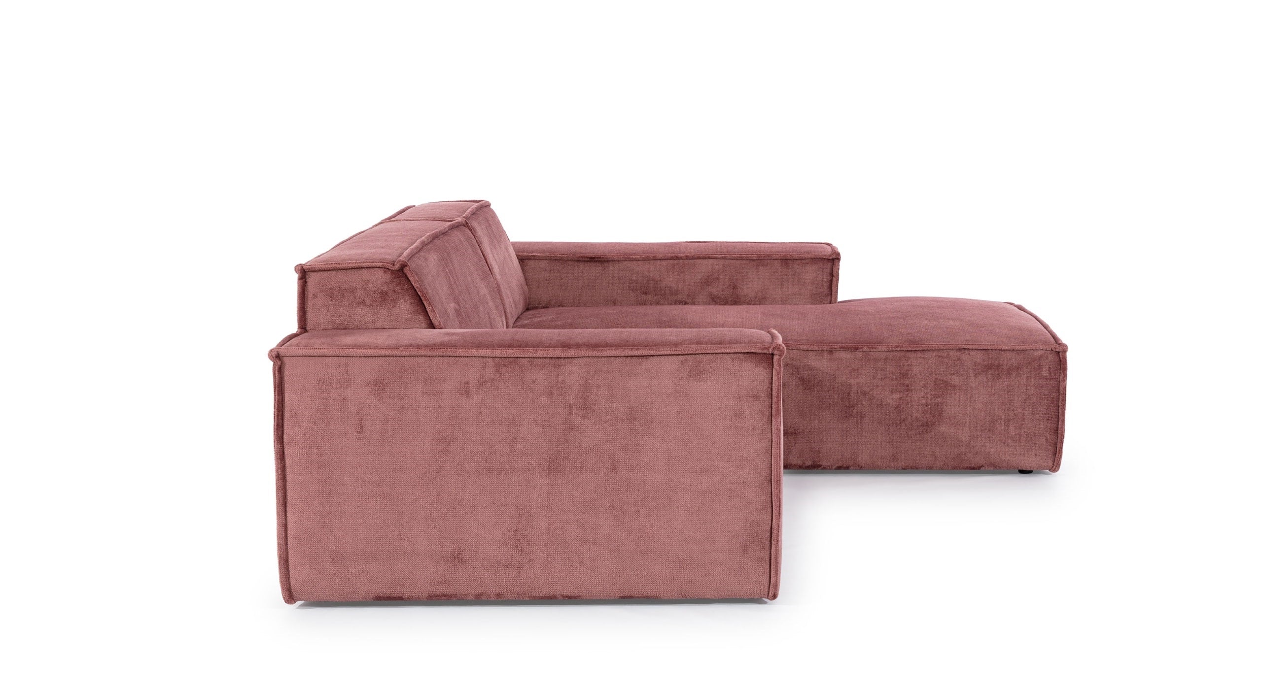 Zijaanzicht van de Hoekbank Sense met chaise longue rechts, uitgevoerd in een warme roze stof. De strakke lijnen en brede armleuningen benadrukken het moderne, minimalistische ontwerp, perfect voor eigentijdse woonruimtes die comfort en stijl combineren.