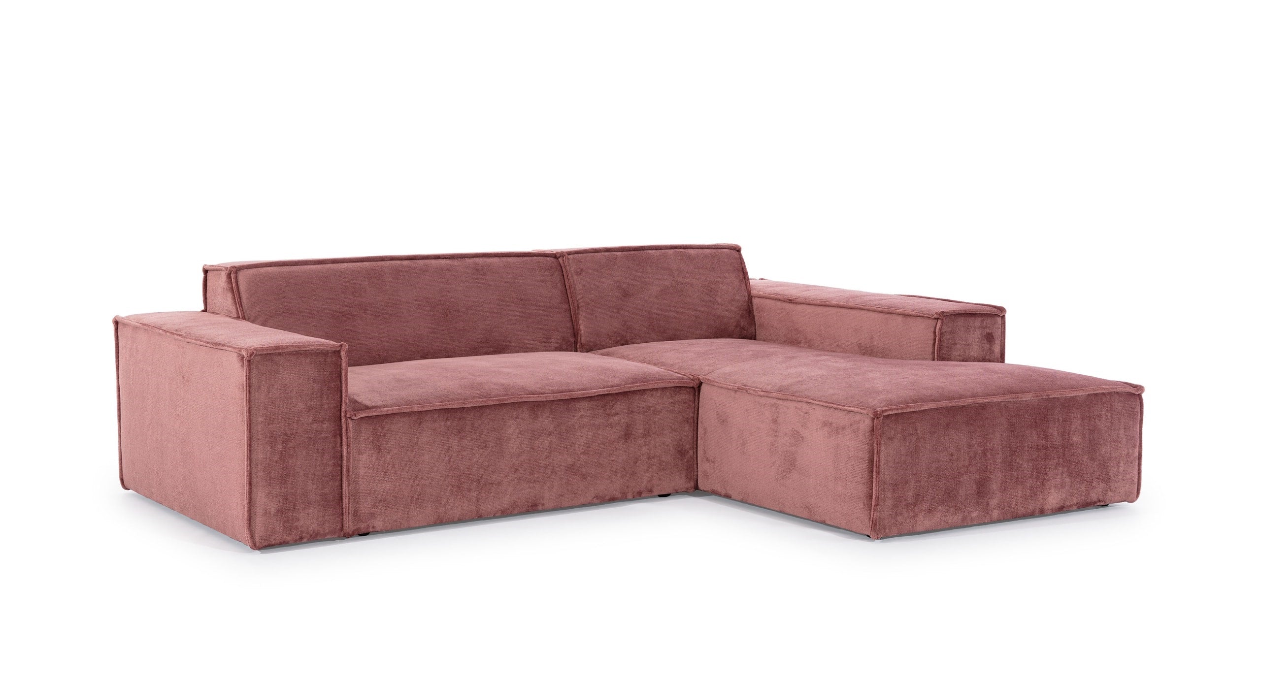 Schuin aanzicht van de Hoekbank Sense met chaise longue rechts, in een warme roze stof. De bank heeft een strak, minimalistisch ontwerp met brede armleuningen en rechte lijnen, ideaal voor een moderne en stijlvolle inrichting in eigentijdse woonruimtes.