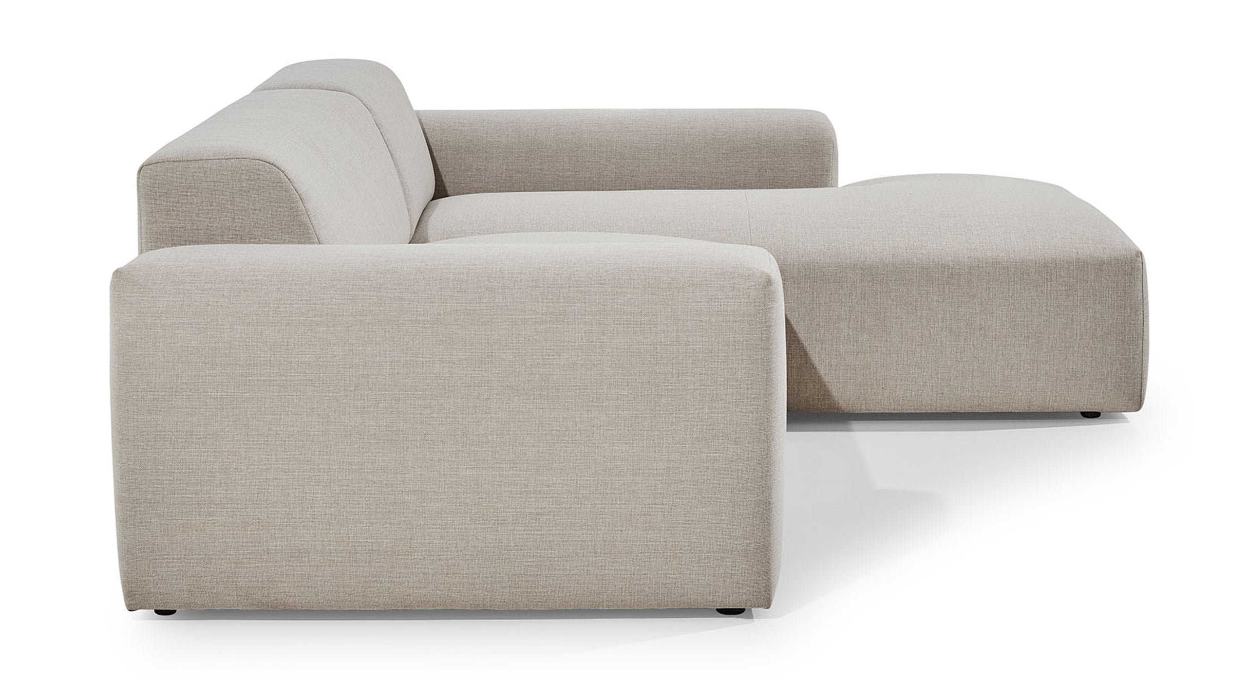 Zijaanzicht van de Hoekbank Vibe met chaise longue rechts, uitgevoerd in een neutrale beige stof. De bank heeft een strak en eigentijds ontwerp met brede armleuningen en een diepe zitting, wat bijdraagt aan een moderne en comfortabele uitstraling in de woonkamer.