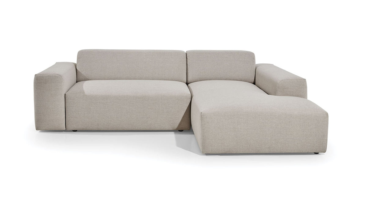 Hoekbank Vibe met chaise longue rechts, uitgevoerd in een neutrale beige bekleding. De bank heeft een strak en modern design met brede armleuningen, ideaal voor een eigentijdse woonkamerinrichting die comfort en stijl combineert.