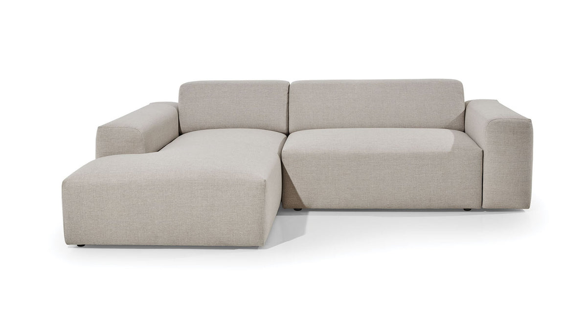 Hoekbank Vibe met chaise longue links, uitgevoerd in een neutrale beige stof. De bank heeft een strak en minimalistisch ontwerp met brede armleuningen en een comfortabele zitting, ideaal voor een moderne en rustgevende inrichting.